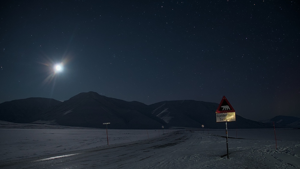 The polar bear sign at night with a view of the Adventdalen valley