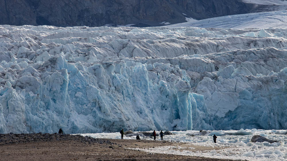 People in front of a blue glacier front on Svalbard