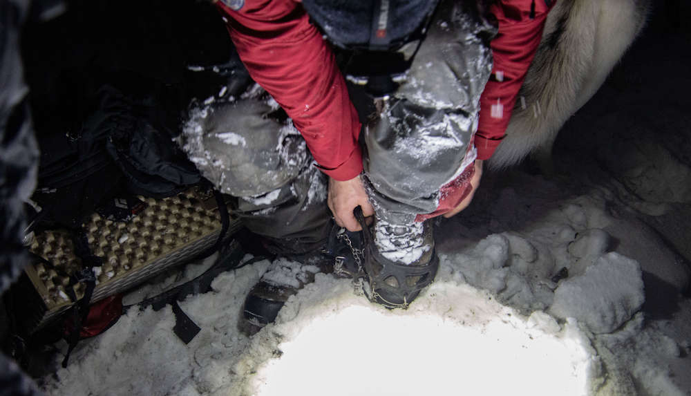 Putting spikes on shoes for a snow hike